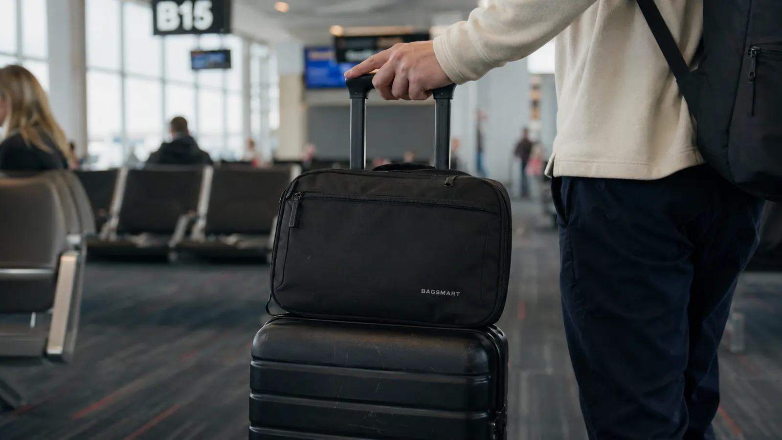 Open FYY electronics organizer sitting on top of a packed carry-on suitcase at an airport terminal